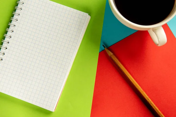 Notebook, pencil and cup of coffee on a multi-colored background. — Stock Photo, Image