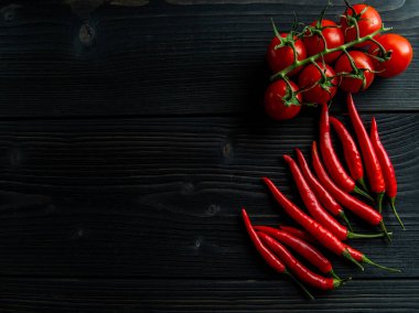 Siyah ahşap bir masada vişneli domates ve biber.