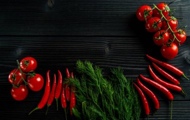 Siyah ahşap arka planda kiraz domatesleri, kırmızı biber ve taze otlar.