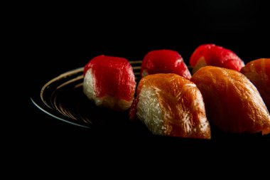 Siyah tabakta somon ve ton balığı suşisi ve siyah ahşap bir arka plan.