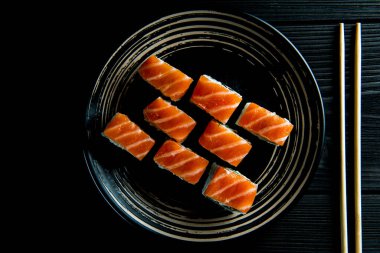 Lezzetli Philadelphia ruloları siyah bir tabakta ve siyah ahşap arka planda