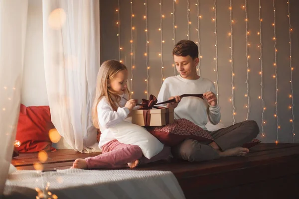 Kids open christmas gift in the Christmas interiors with lights.
