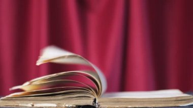 Kırmızı perdenin üzerindeki eski bir kitap. Sayfalar sihirli bir şekilde kendilerini çevirirler, ya da rüzgar. Yalnızlık ve roman okumak. İlginç hikayeler, fantastik hikayeler. Yavaş çekimde kartlar taraf değiştirir.