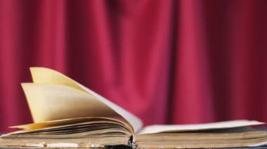 Kırmızı perdenin üzerindeki eski bir kitap. Sayfalar sihirli bir şekilde kendilerini çevirirler, ya da rüzgar. Yalnızlık ve roman okumak. İlginç hikayeler, fantastik hikayeler. Yavaş çekimde kartlar taraf değiştirir.