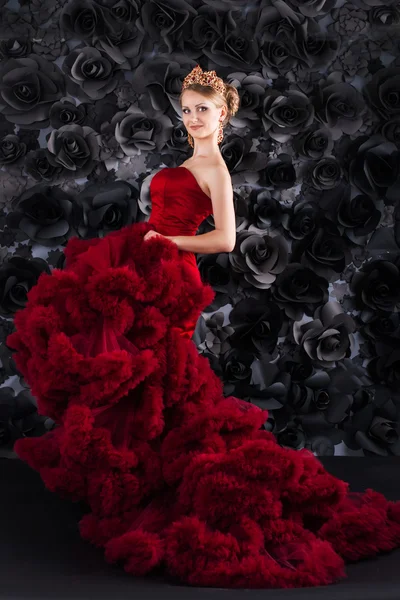 Beautiful young blonde woman in red long dress with fluffy skirt on a black background. queen, golden crown on the head, golden curls, passionate girl in red — Φωτογραφία Αρχείου