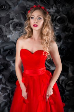 Güzel sarışın genç kadın yaprakları siyah bir zemin üzerine kırmızı uzun elbiseli. Kraliçe, baş, altın kırmızı çember bukleler, kırmızı, kırmızı dudaklar kadınla, Prenses Peri masalı gelen tutkulu kız, 