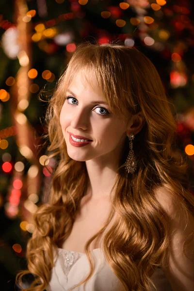 Giovane bella donna bionda in abito bianco a Natale, donna in una bella stanza con un albero di Natale e candele, una ragazza con regali, capelli dorati, donna felice anno nuovo, ragazza rossa sorridente — Foto Stock