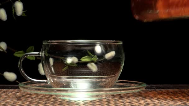 Closeup of teapot pouring tea into glass cup