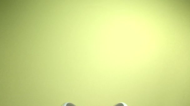 緑の背景に英語のテキストで表示されるモダンなイヤホン — ストック動画