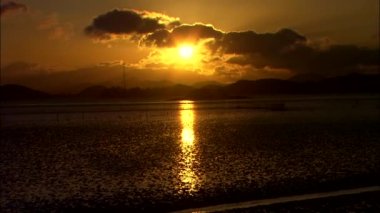 Deniz yüzeyinde yansıtan turuncu günbatımı