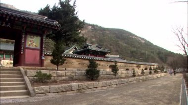 Çit çekim ve arka plan üzerinde Dağları ile geleneksel Kore tapınak kapısı kaydırma