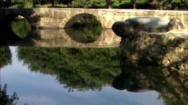 Kore geleneksel tapınağın topraklarında suda yansıtan taş köprüsü 