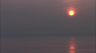 Deniz yüzeyinde yansıtan turuncu günbatımı