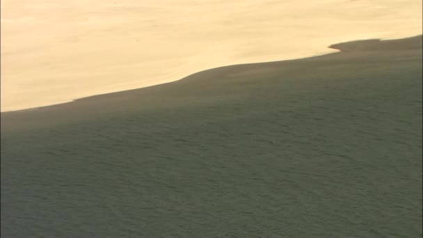 Волнистая поверхность реки возле песчаного побережья — стоковое видео