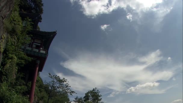 人们进入韩国的传统寺庙建筑在背景的树和山 — 图库视频影像