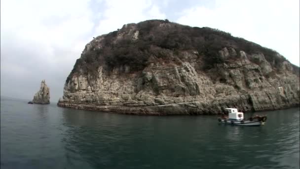 Paisaje marino con barco flotando cerca de isla rocosa — Vídeos de Stock