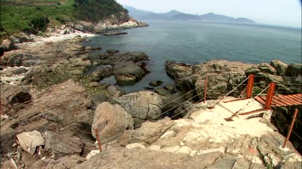 Paysage du littoral rocheux avec pont en bois rouge sur fond de mer 