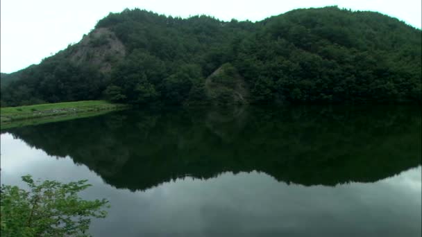 Озеро окружено холмами с деревьями — стоковое видео