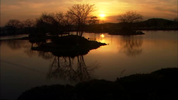 Orange solnedgång reflektera över sjön yta — Stockvideo