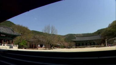 Bölge ağaçlar ve dağlar arka plan üzerinde Güney Kore'de geleneksel temple binaların üzerinde yürüyen insanlar