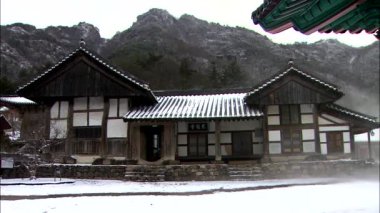 Veranda zemin üzerine Dağları ile geleneksel Kore Tapınağı binaların kar fırtınasında