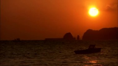 Deniz yüzeyinde yansıtan turuncu günbatımı