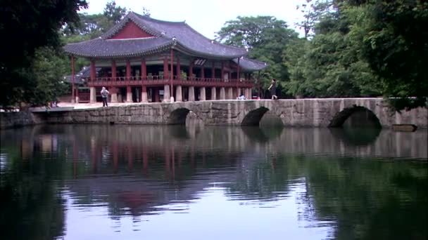 人在石桥梁与传统的韩国寺庙大厦在背景下行走 — 图库视频影像