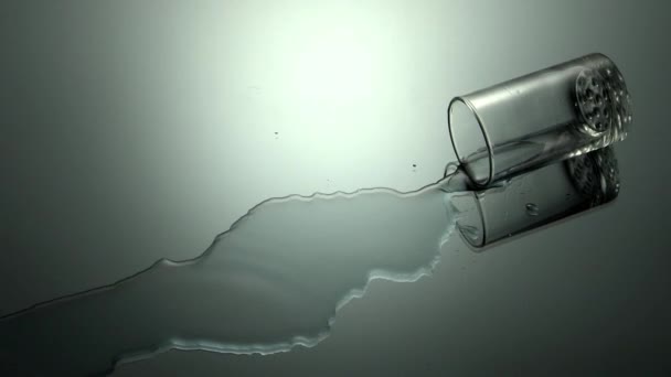 Glas Wasser Fällt Und Plätschert Vor Grauem Hintergrund — Stockvideo