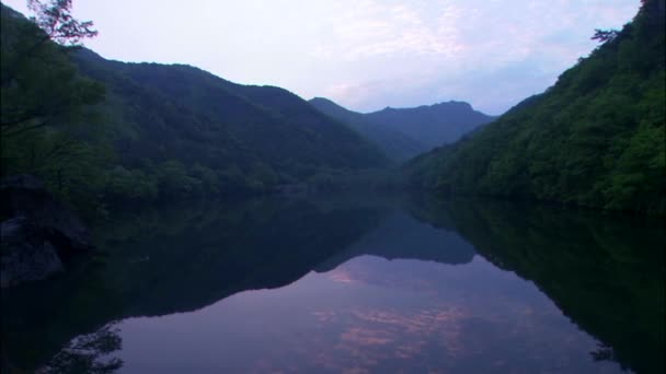 Пагорби, що відображаються на дзеркальній поверхні озера — стокове відео