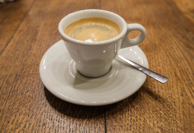 Küçük bir restoranın ahşap masasında bir fincan kahve.