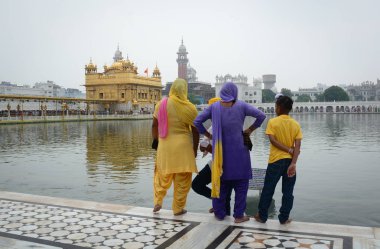 Amritsar, Hindistan - 25 Temmuz 2015. Ayakta ve Amritsar, Hindistan altın tapınağı görmek bir Sih ailesi. Sihizm en kutsal Gurdwara altın tapınak olduğunu.