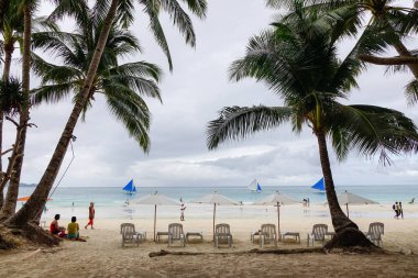 Boracay, Filipinler - 17 Aralık 2015. Palmiye ağaçları beyaz Beach Boracay, Filipinler ile rahatlatıcı sandalye.