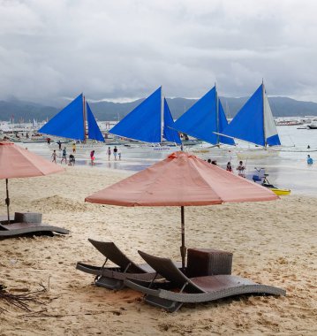 Boracay, Filipinler - 17 Aralık 2015. Rahatlatıcı sandalye şemsiye ve yelkenli beyaz Beach Boracay, Filipinler.