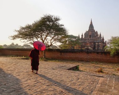 Bir Budist rahip acient pagoda Bagan, Myanmar, şemsiye ile kırmızı elbise içinde.