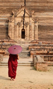 Bir Budist rahip acient pagoda geliyor şemsiye ile kırmızı elbise içinde.