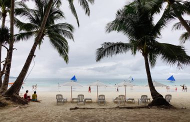 Boracay, Filipinler - 17 Aralık 2015. Rahatlatıcı sandalye beyaz Beach Boracay, Filipinler palmiye ağaçları ile. Boracay bir tropik ada çarpıcı beyaz kumlu plajları tarafından çevrili olduğunu.