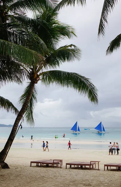 Boracay, Filipinler - 17 Aralık 2015. Beyaz plaj Boracay, Filipinler plam ağaçları ile insanlar. Boracay Adası çok sayıda seyahat yayınlar ve kurumları ödül aldı.