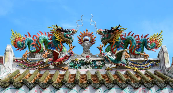 An image of dragon on a roof top of dragon Chinese temple. Dragon statue under blue dragon sky.