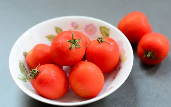 Bowl full of tomato fruits on the stone floor. Closed up.