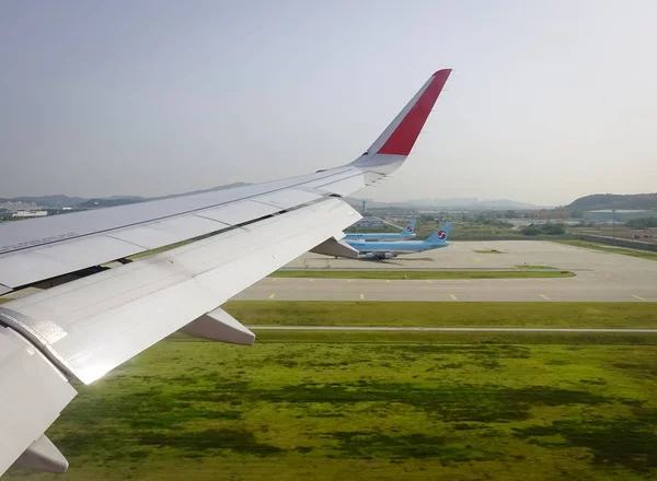 Wing of airplane with the runway background. View from window seat.