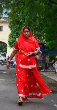Jaipur, Hindistan - 27 Temmuz 2015. Jaipur, Hindistan sokakta yürüyen kırmızı sari Hintli bir kadın. Pembe şehir olarak bilinen Jaipur, Hindistan bir turistik yer.