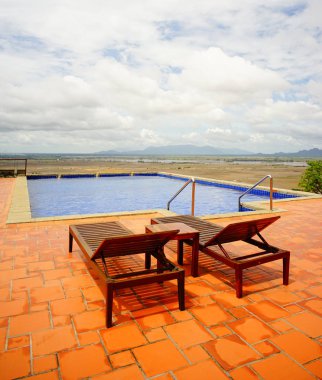 Güney Vietnam kırsal pirinç alan arka plan ile güzel yüzme havuzunda rahatlatıcı sandalye.