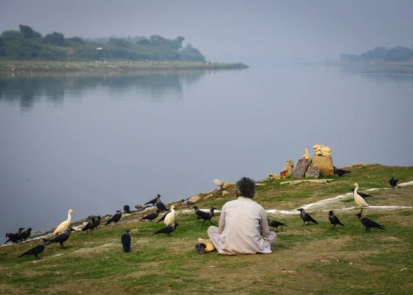 Indiase man voedt vogels op rivieroever — Stockfoto
