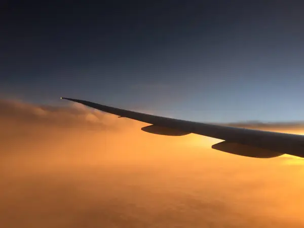 Wing of airplane flying above the clouds — Stock Photo, Image