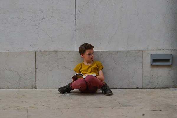 Un ragazzo carino leggere libro sulla piazza principale — Foto Stock