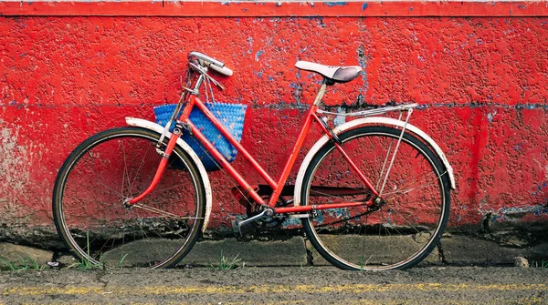 Uma bicicleta velha contra a parede vermelha — Fotografia de Stock