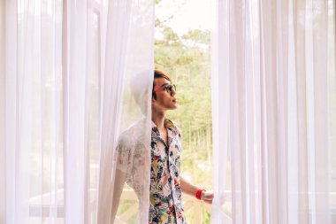 Asyalı yakışıklı adam balkonda duruyor. 