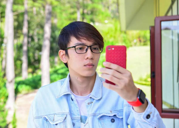Asyalı genç adam akıllı telefondan selfie çekiyor. — Stok fotoğraf