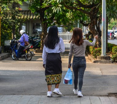 Vientiane, Laos - 29 Ocak 2020. Vientiane, Laos 'ta sokakta yürüyen genç kadınlar. Vientiane, Mekong Nehri kıyısındaki Laos 'un başkenti ve en büyük şehridir..