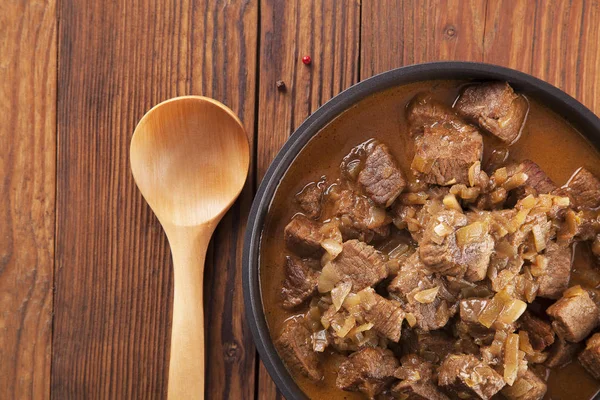 Beef stew - wooden background — Stock Photo, Image